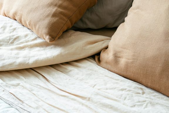 Literie avec des coussins beiges et une texture en lin clair.